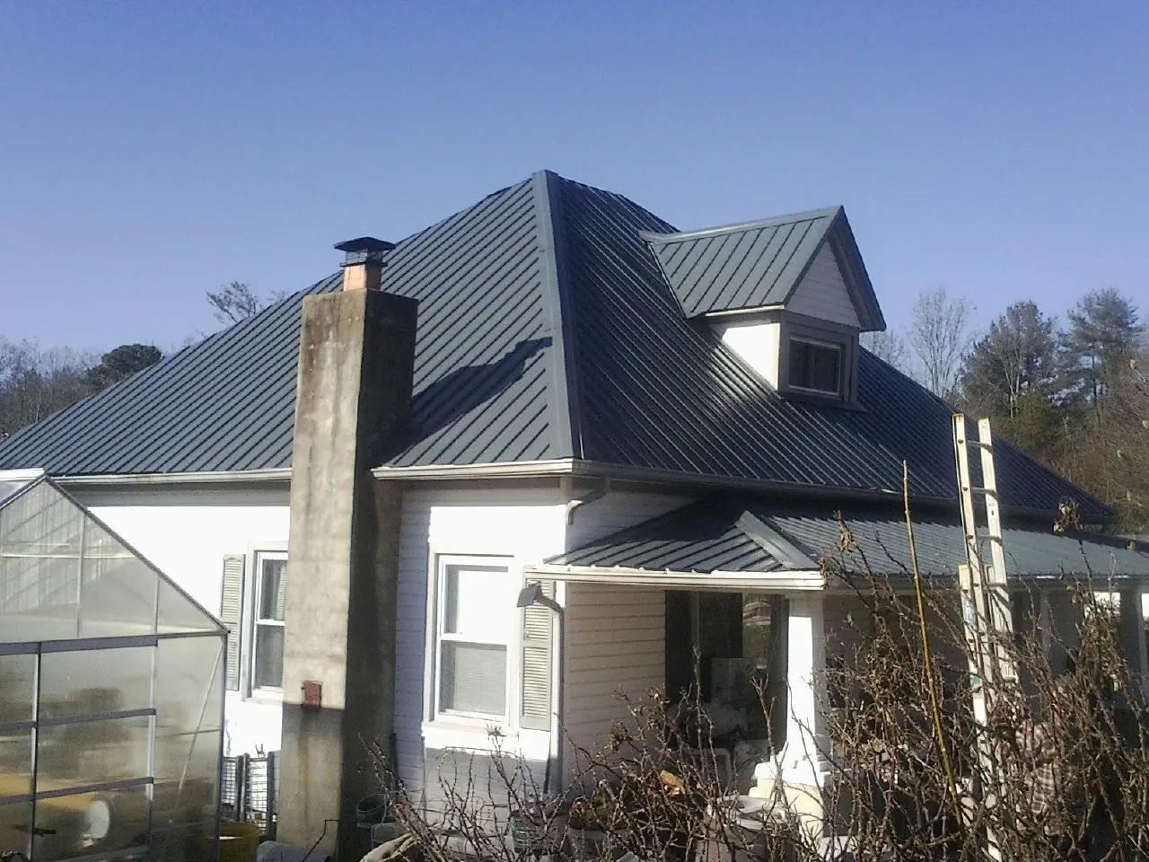 Dark blue standing seam metal roof on a white farmhouse with dormer — Slate & Tile Roof Repair by Roofing Brothers in Silverado