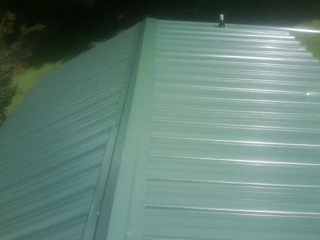 New green metal panels meeting at the ridge of a roof — Flat Roof Repair work by our crew in Silverado