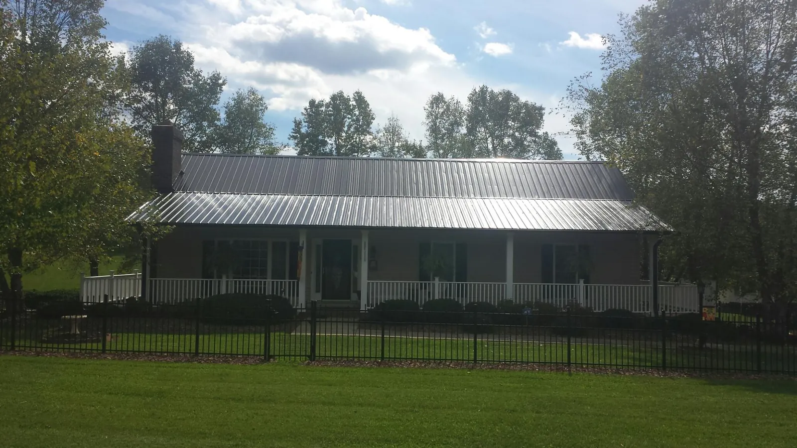 Gray metal roof on a brick ranch with a full width front porch — Gutter Guard Installation work by our crew in Silverado